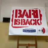 Qui, al piano inferiore dell�edificio, veniamo accolti nel corridoio d�ingresso dallo striscione �Bari is Back�, creato nel 2020 per incitare la squadra durante i playoff di serie C